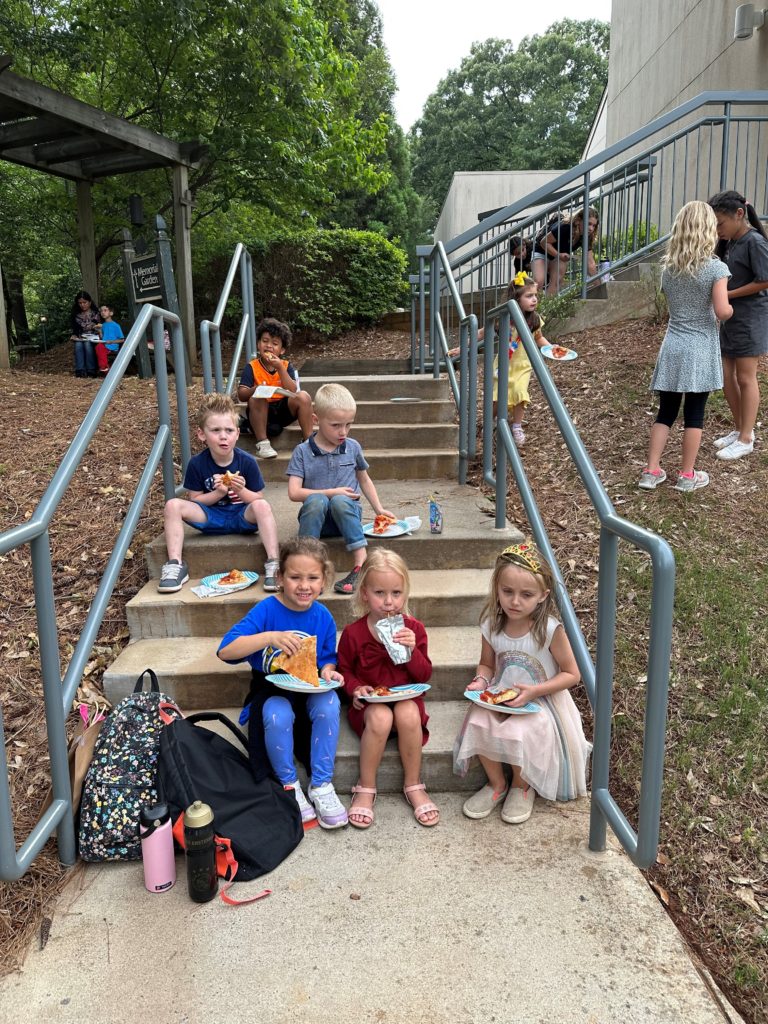 Children having a snack outside on some stairs on the last day of school